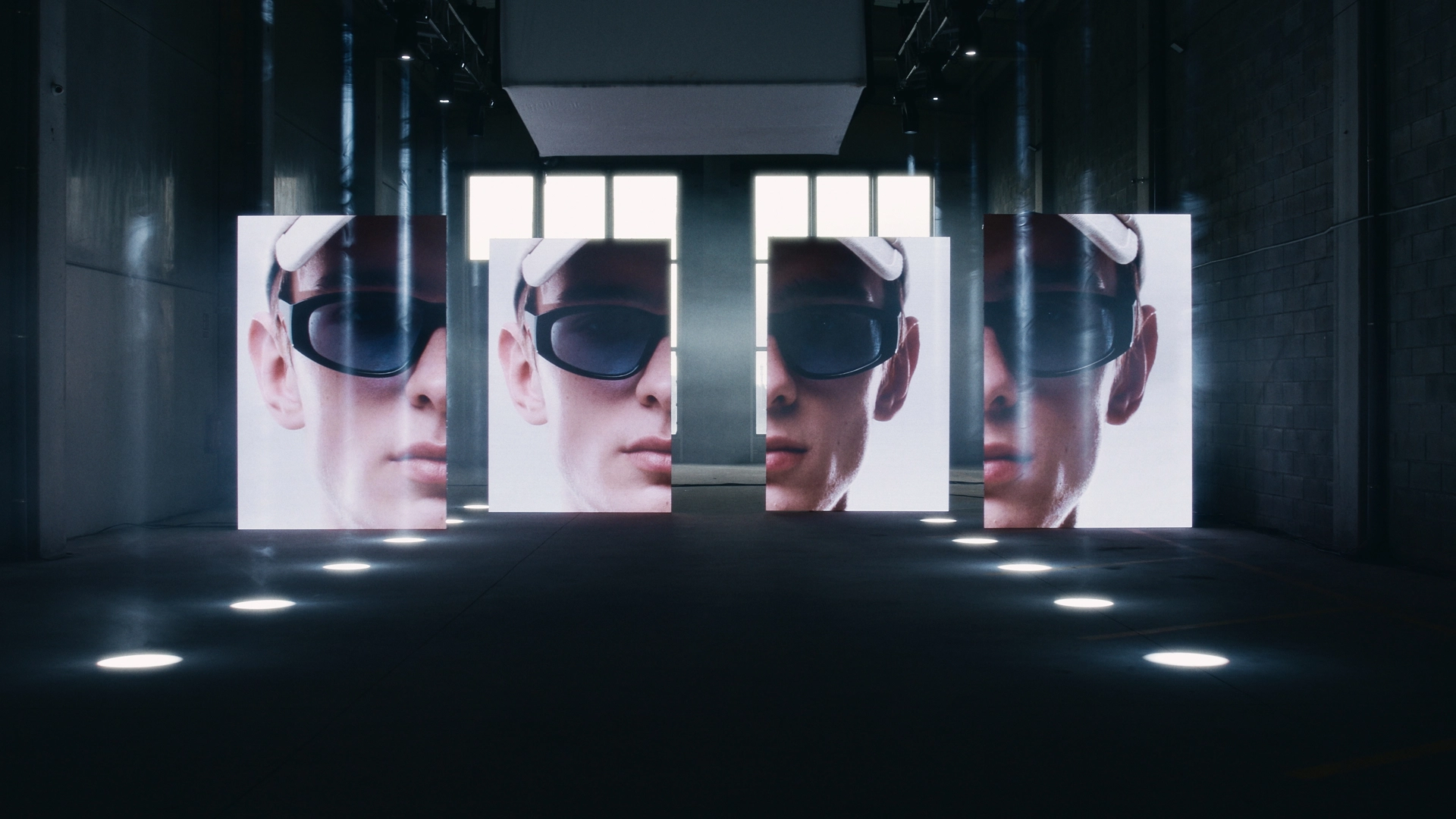 Cuatro pantallas led verticales separadas mostrando distintas partes de la cara de un modelo